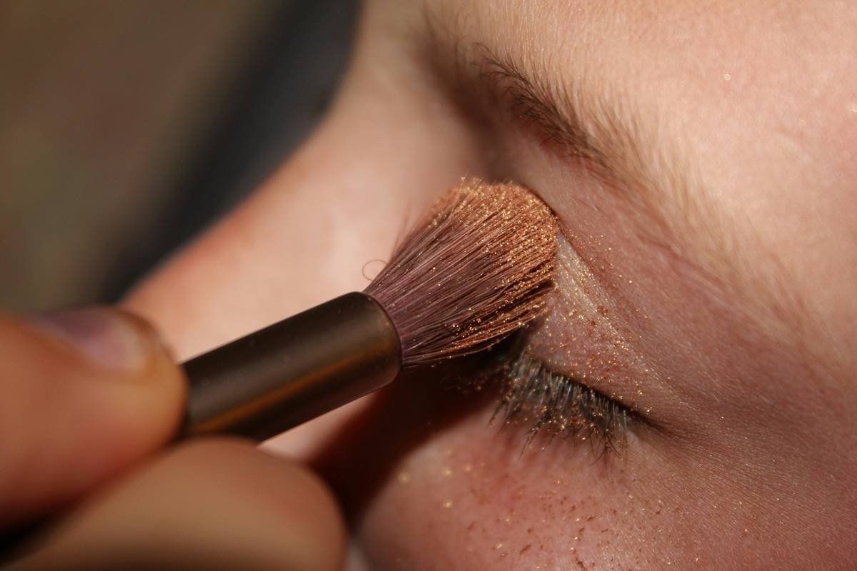 Infographic showing how directional lighting affects makeup visibility: flat light vs. 45-degree key light with fill. Highlights how under-eye shadows disappear or intensify based on angle.